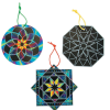 Three scratch art ornaments with hanging cords in different shapes: a circular ornament with a colorful mandala flower design, an octagonal ornament with a geometric star pattern partially scratched, and a square star-shaped ornament with a colorful starburst design, all on black scratch art backgrounds.