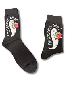 Pair of black crew socks featuring Will-O-the Whisperer, a friendly white ghost wearing glasses and holding a colorful stack of books. The phrase “I'm Booooooked” curves around the ghost in white lettering. One sock is shown unfolded and the other folded against a white background.