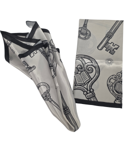 White scarf with a black border and a pattern of ornate antique keys with open-book designs, shown folded and draped