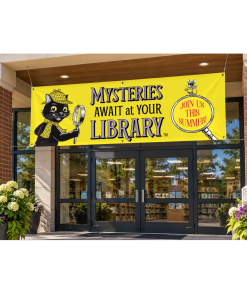 Exterior of a public library with a large yellow Mysteries Await at Your Library vinyl banner hanging above the entrance. The banner features Inspector Whiskers holding a magnifying glass and Nibbleton Finch perched above the words “Join Us This Summer!”