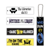 Five PVC Reader Ribbons featuring mystery-themed designs arranged on a white background. Four horizontal ribbons read “The Librarian Did It!” with a detective hat and sunglasses, “Mysteries Await at Your Library,” “Case Closed” with a yellow Top Secret folder, and “I’m on the Case” with Inspector Whiskers peeking over the edge. A fifth vertical black ribbon reads “Who Dun It?” and features a masked book thief. Each ribbon has an attachment hole, with a silver ball chain shown on the vertical design.
