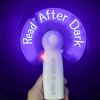 Handheld LED light-up fan with a white handle featuring the purple Mysteries Await at Your Library slogan. Spinning purple blades display the illuminated words “Read After Dark” in bright white letters against a dark purple background.