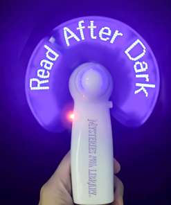 Handheld LED light-up fan with a white handle featuring the purple Mysteries Await at Your Library slogan. Spinning purple blades display the illuminated words “Read After Dark” in bright white letters against a dark purple background.